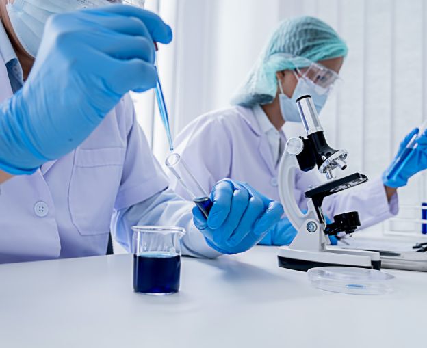 Researchers working in a laboratory with pipettes and microscopes.